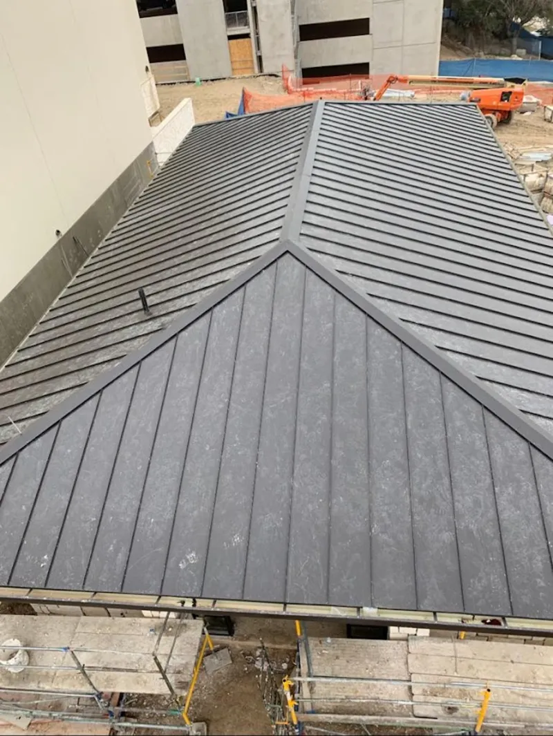 Commercial metal roof construction with crane equipment in Bell Gardens